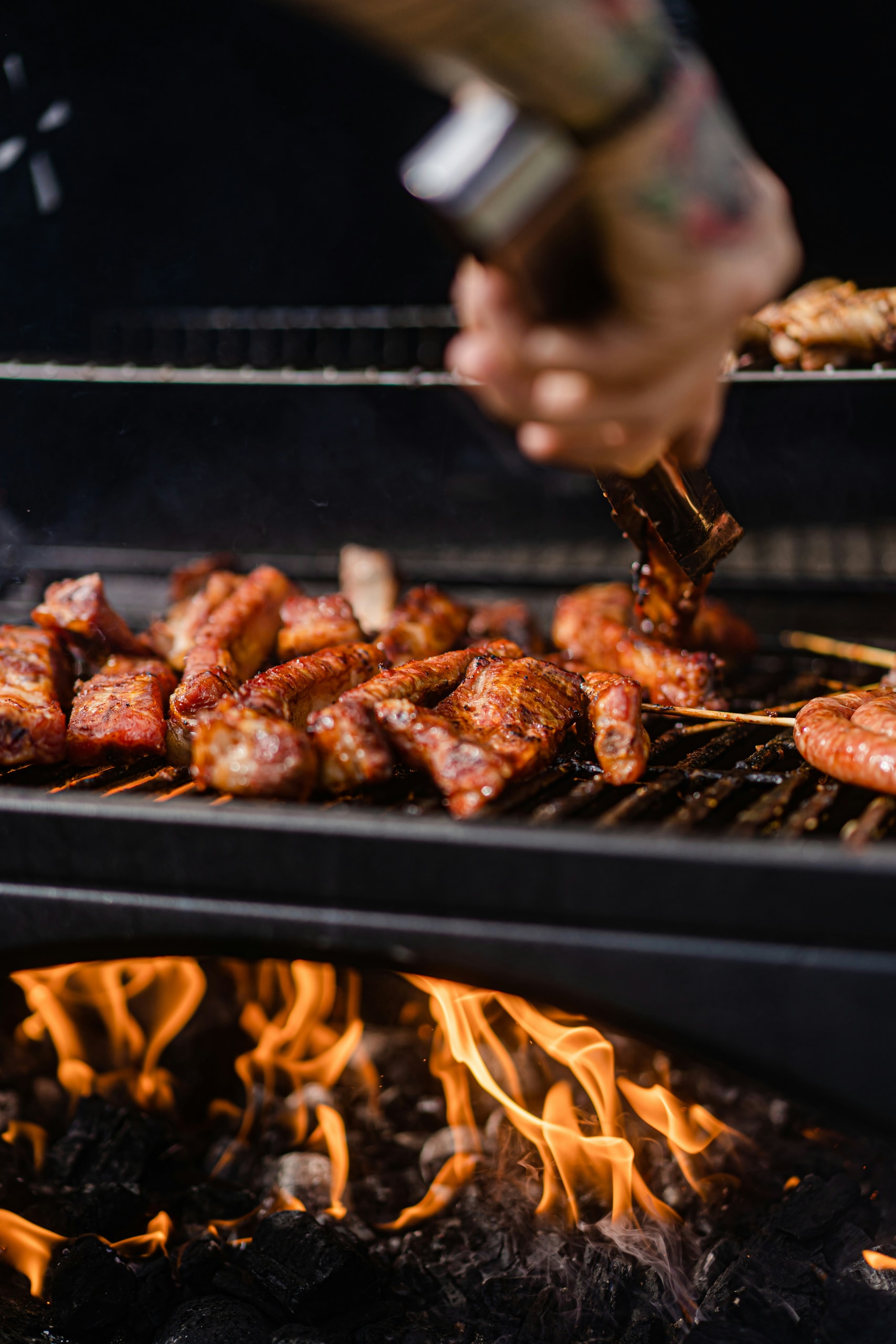 Meat being turned over open flames on the grill