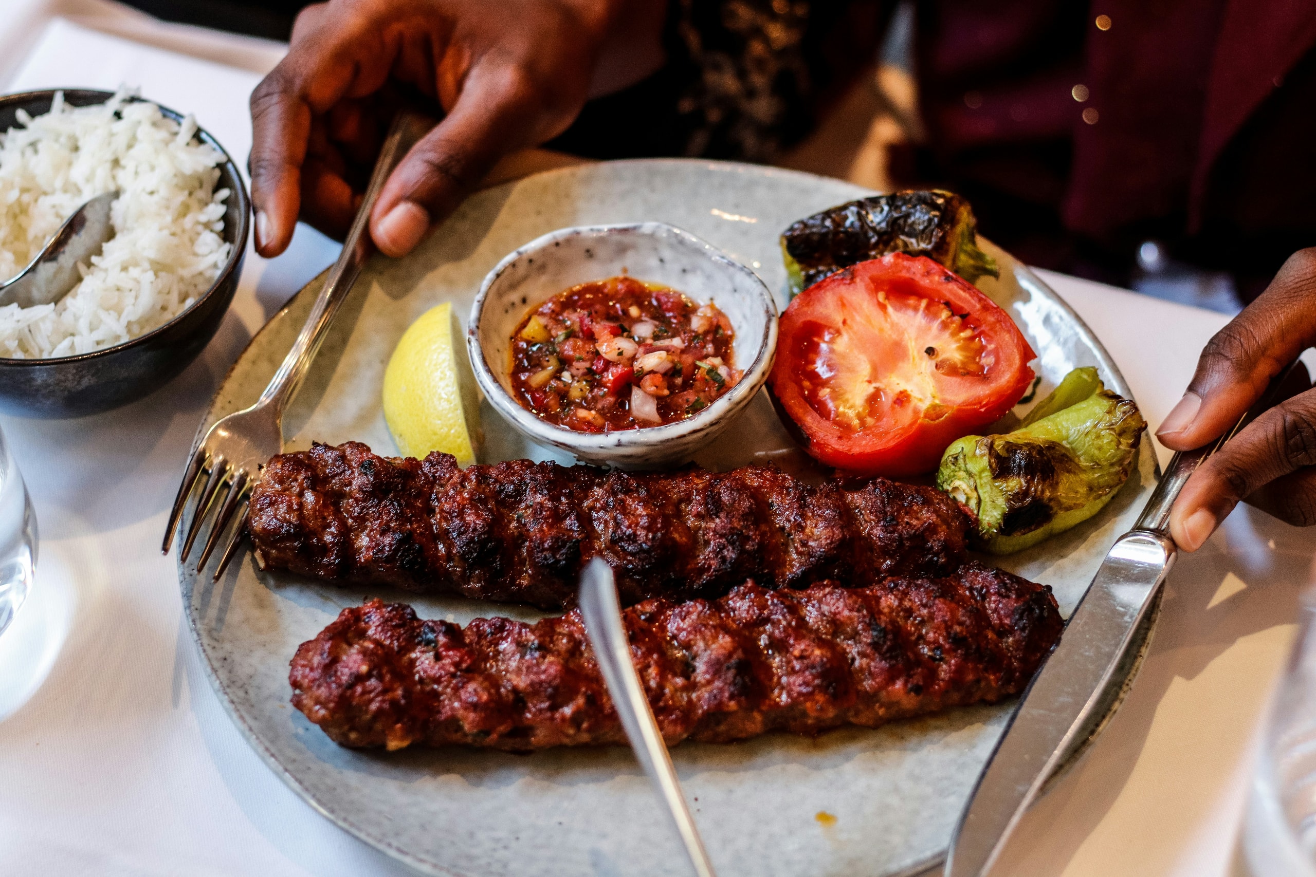 Two koobideh kebabs with grilled tomato and pepper