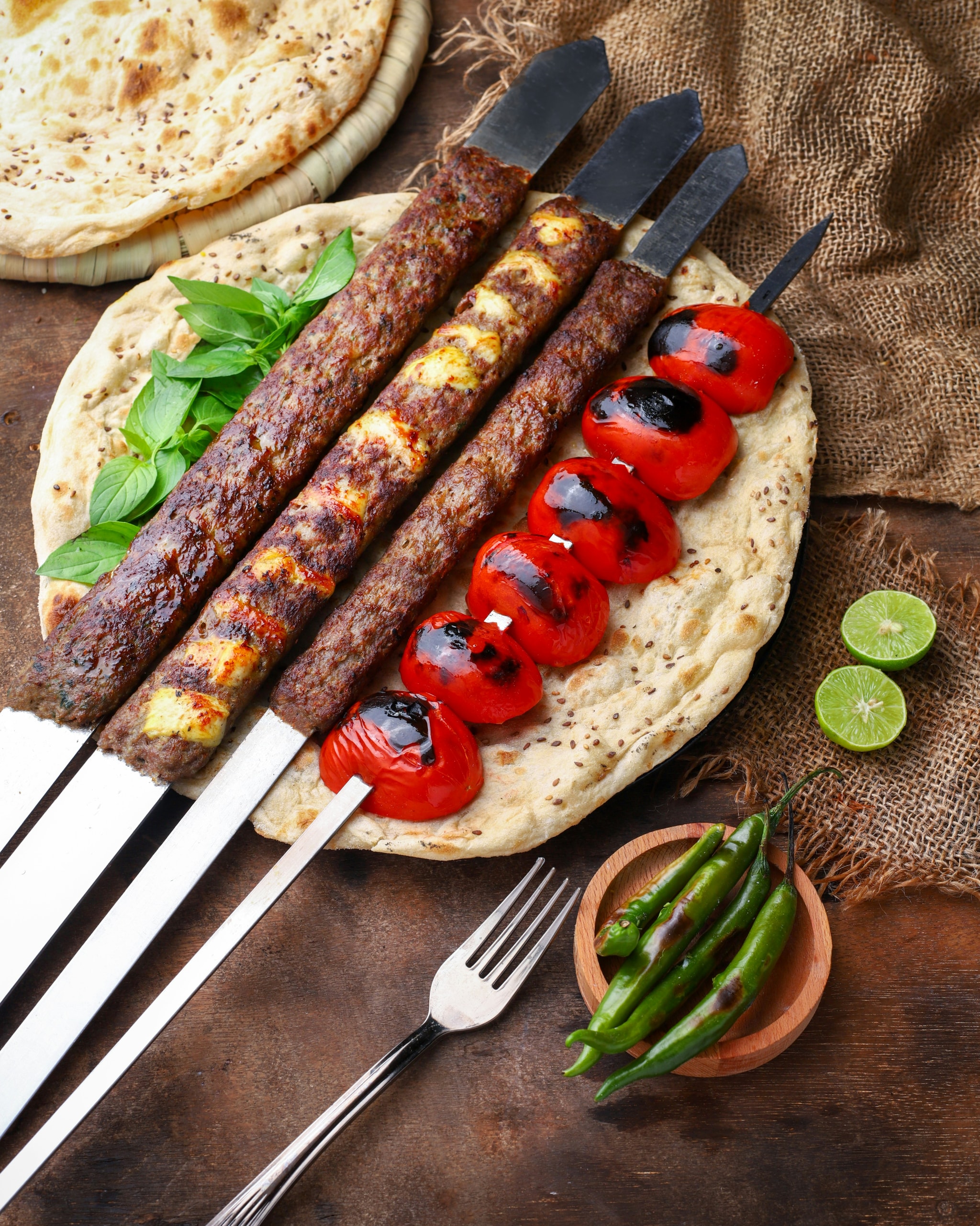 Koobideh and chicken kebab skewers with grilled tomatoes on flatbread